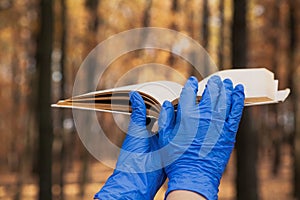 Hands in rubber gloves hold book in forest