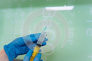 Hands in rubber gloves hold a disposable medical syringe with the drug