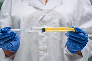 Hands in rubber gloves hold a disposable medical syringe with the drug