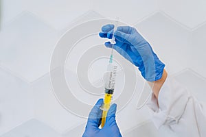 Hands in rubber gloves hold a disposable medical syringe with the drug