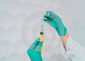 Hands in rubber gloves hold a disposable medical syringe with the drug