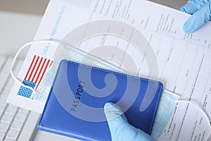 Hands in rubber gloves holding passport and documents for US visa closeup