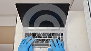 Hands in rubber gloves working on a laptop