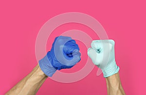 Hands in rubber medical gloves different color clenched into fist, sign of joint fight against virus epidemic or adversity