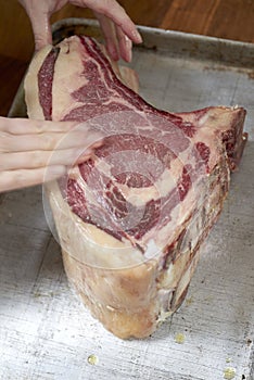 Hands Rubbing Salt on Cut of Uncooked Beef Cut on Aluminum Tray