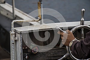 Hands on rudder wheel vintage boat closeup.