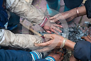 Hands of rural minority people warming up around the fire during the cold weather days in mountaious region in Vietnam