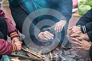 Hands of rural minority people warming up around the fire during the cold weather days in mountaious region in Vietnam