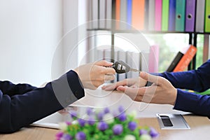 Hands of sales car dealership giving keys to customer