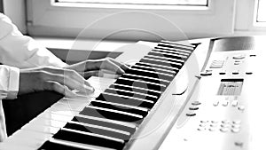 hands of a schoolgirl in a white shirt playing on the piano keys. selective focus