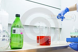 Hands of the scientist in the laboratory mixes with transfusion a chemical materials from graduated cylinder to beaker. Concept