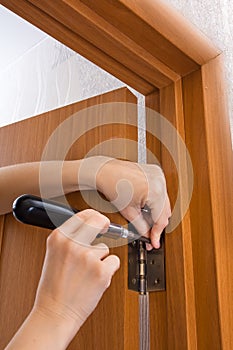Hands screwing hinge on a door