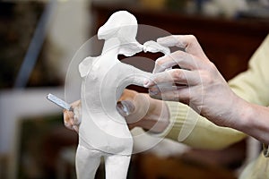 Hands of sculptor works with statuette. photo