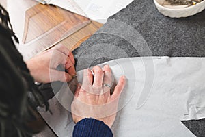 Hands of seamstress fixing template to fabric
