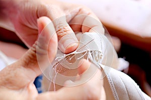 Hands of seamstress at work on the wooden chair with her cloth , hand made soft toys sewing with felt and needle