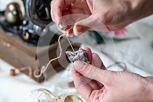 Hands of seamstress working with needle and thimble close-up