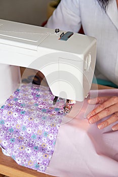 Hands of seamstress working on sewing machine