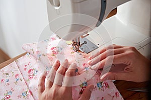 Hands of seamstress working on sewing machine