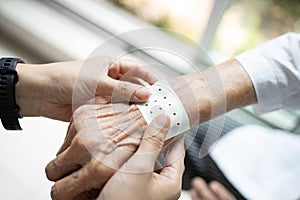 Hands of senior with analgesic sheet,chinese plaster to stick on the wrist of the old elderly to relieve muscular pain,plaster photo