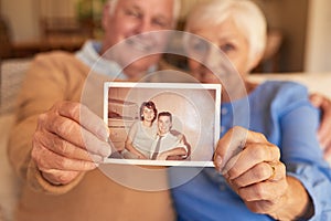 Hands of senior couple holding their youthful photo at home