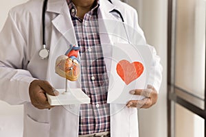 Hands of senior doctor holding greeting card with red heart