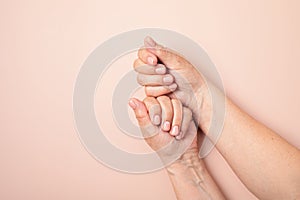 Hands of a senior woman with nude manicure