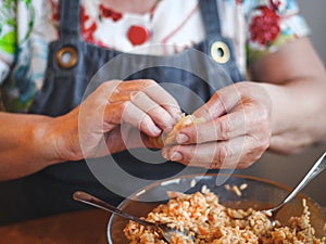 Hands of a senior woman wrapping a leaf of sauerkraut with rice-meat filling