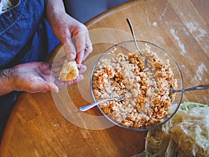 Hands of a senior woman wrapping a raw sauerkraut stuffed cabbage stuffed with rice and meat