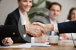 Hands of senior and young businessmen shaking at group meeting