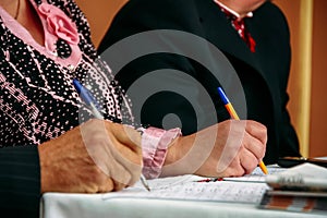 Hands of seniors with pens