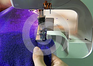 Hands serging with machine on purple blanket