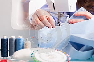 Hands on sewing machine with reels of colour threads and sewing