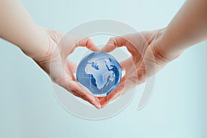 Hands in shape of heart  holding blue glass globe of Africa and Europe