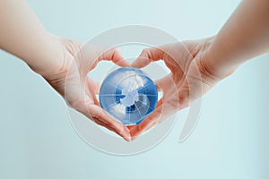 Hands in shape of heart  holding blue glass globe of South Pole