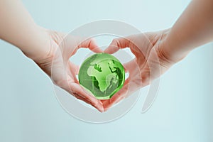 Hands in shape of heart  holding green glass globe of Africa and Europe