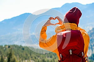 Hands in shape of love heart. Love green energy. Woman making heart with her hands. Female hiker on top of mountaines