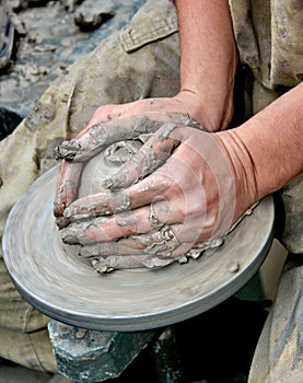 Hands shaping clay on potter's wheel photo