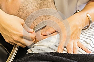 Hands shaving a man`s beard