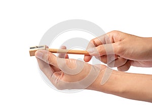 Hands shaving wooden pencil with pencil sharpener isolated on white background. Stationary items