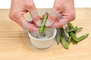 Hands shelling peas