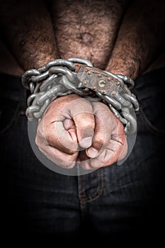 Hands of a shirtless man chained with a chain and a padlock