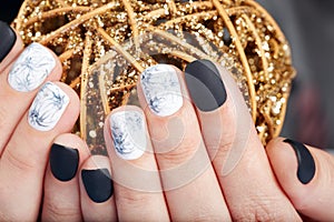 Hands with short manicured nails colored with black and white nail polish