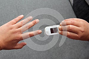 Hands show the use of the oximeter to measure the patient`s oxygenation and pulse for suspected Covid-19 in the new normality due