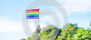 Hands showing LGBTQ Rainbow flag on nature background. Support Lesbian, Gay, Bisexual, Transgender and Queer community and Pride