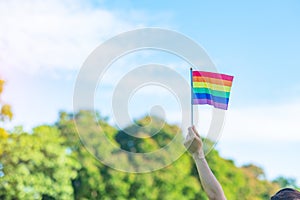 Hands showing LGBTQ Rainbow flag on nature background. Support Lesbian, Gay, Bisexual, Transgender and Queer community and Pride