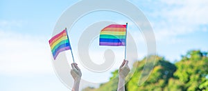 Hands showing LGBTQ Rainbow flag on nature background. Support Lesbian, Gay, Bisexual, Transgender and Queer community and Pride