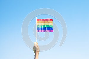 Hands showing LGBTQ Rainbow flag on nature background. Support Lesbian, Gay, Bisexual, Transgender and Queer community and Pride