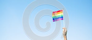 Hands showing LGBTQ Rainbow flag on nature background. Support Lesbian, Gay, Bisexual, Transgender and Queer community and Pride