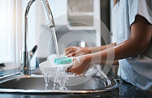 Hands, sink and washing dishes with a person in the kitchen of a home to wash a plate for hygiene. Water, bacteria and