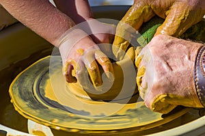 hands of the skilled master Potter and children's hands, training of the kid to production of pottery on a Potter's wheel